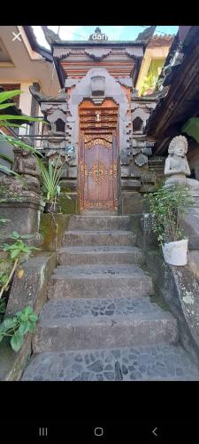 a set of stairs leading to a large wooden door at Gusti Home Stay Ubud in Ubud