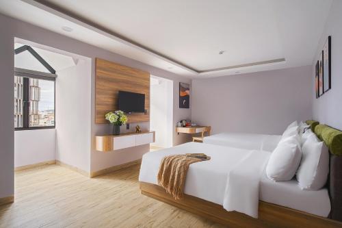 a white bedroom with a bed and a tv at Nature Hotel - Win Happy in Da Lat