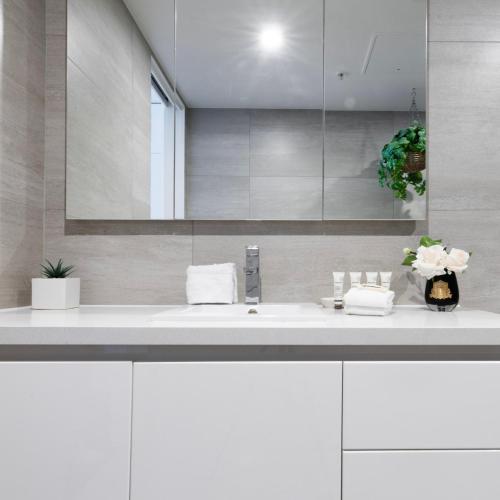 a white bathroom with a sink and a mirror at Views for Days - Luxe 4BR Stay with Pool & Hot Tub in Melbourne