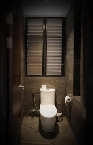 a bathroom with a toilet with a window and a hose at Hug Jang Loei Garden & Resort in Ban Na Dan