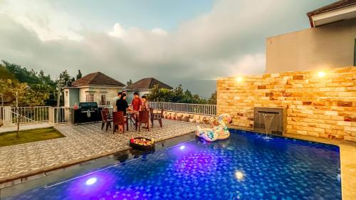 a couple standing next to a swimming pool in a house at SpringHills Villa Panderman Batu - Private Pool in Tlekung