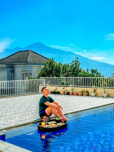 a boy sitting on a toy in the water next to a pool at SpringHills Villa Panderman Batu - Private Pool in Tlekung