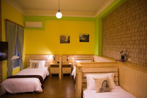 a bedroom with two beds and a yellow wall at 輕旅小站 Soft Travel Hostel in Taitung City