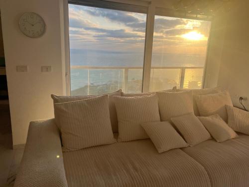 a white couch with pillows in front of a window at Mafruma in H̱adera