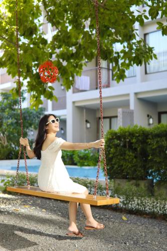 a woman in a dress sitting on a swing at Proud Phuket, Naiyang Beach in Nai Yang Beach