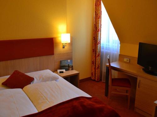 a hotel room with a bed and a desk and a television at Hotel-Gasthof Rotes Roß in Markt Einersheim