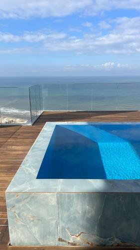 a blue swimming pool on a balcony with the ocean at Mafruma in H̱adera
