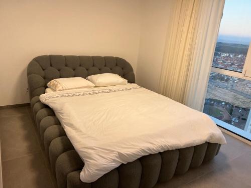 a bed in a room with a large window at Mafruma in H̱adera