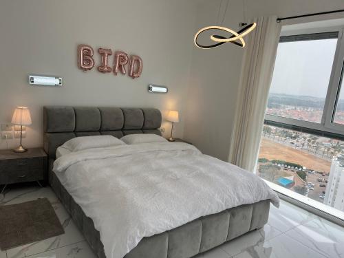 a bedroom with a large bed and a large window at Mafruma in H̱adera