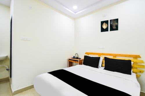 a white room with a bed with black pillows at Super Collection O Adibatla Hyderabad in Ibrāhīmpatan