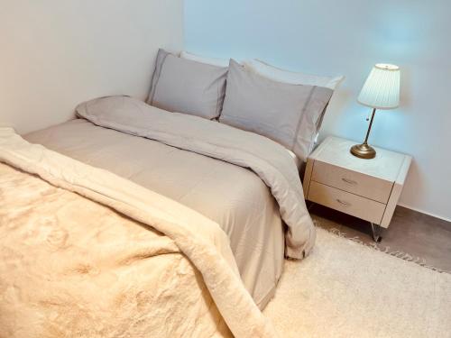 a bedroom with a bed and a night stand with a lamp at Mafruma in H̱adera