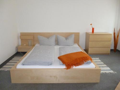 ein Schlafzimmer mit einem Holzbett mit einer orangefarbenen Decke in der Unterkunft City-Apartment Adlergasse Dresden in Dresden