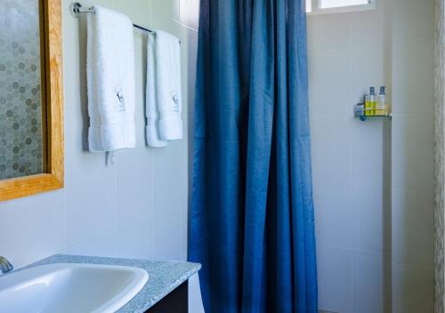a bathroom with a blue shower curtain and a sink at Coral Apartments in Puerto Ayora