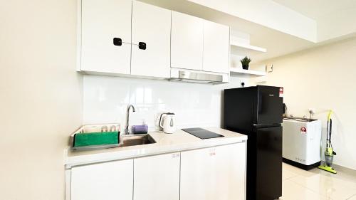 a kitchen with white cabinets and a black refrigerator at Tulip Residences by Manhattan Group in Shah Alam
