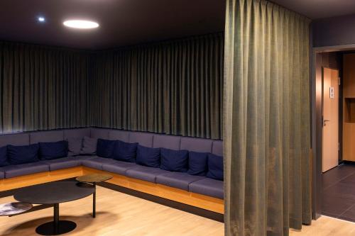 a living room with a blue couch and a table at Scandic Hamburg Emporio in Hamburg