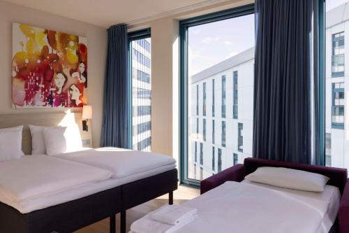 a hotel room with two beds and a large window at Scandic Hamburg Emporio in Hamburg