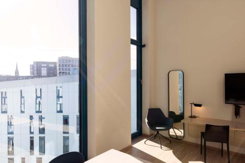 a room with a large window with a desk and chairs at Scandic Hamburg Emporio in Hamburg