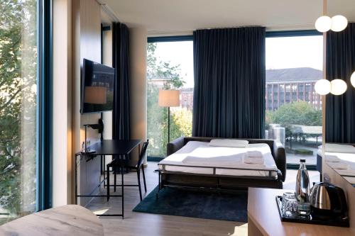 a bedroom with a bed and a desk and a large window at Scandic Hamburg Emporio in Hamburg