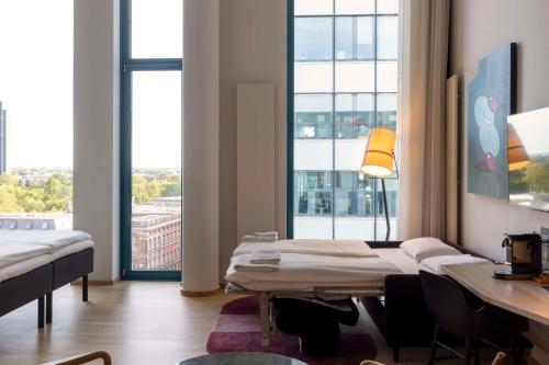 a room with two beds and a desk and a window at Scandic Hamburg Emporio in Hamburg