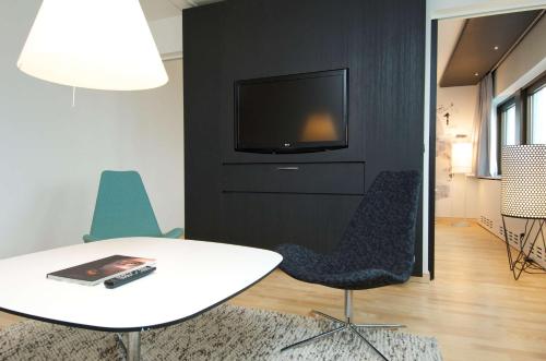a living room with a table and a tv on a wall at Scandic Copenhagen in Copenhagen