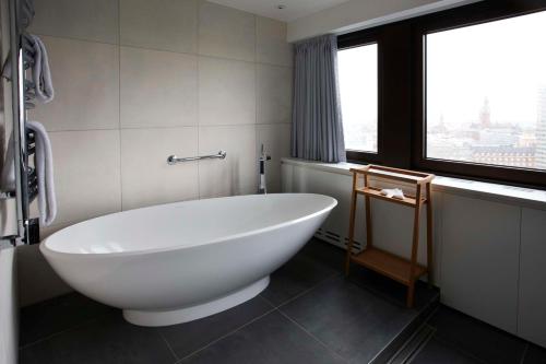 a white bath tub in a bathroom with a window at Scandic Copenhagen in Copenhagen