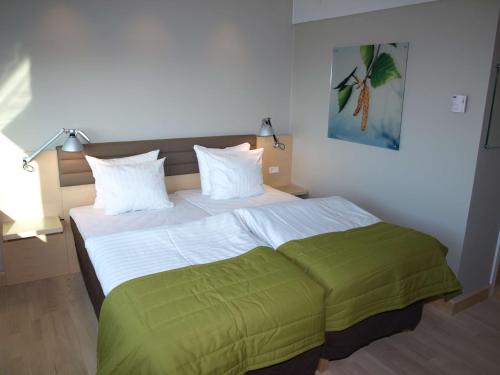 a bedroom with a large bed with green sheets at Scandic Olympic in Esbjerg