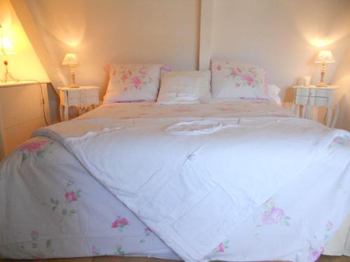 a large white bed with pink flowers on it at Lamaison du phare honfleur chambres d'hotes et jacuzzi privé in Honfleur