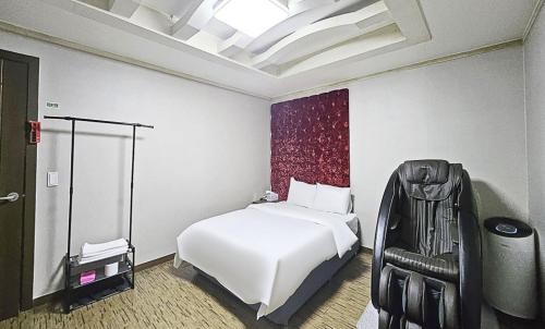 a bedroom with a white bed and a black chair at Nobotel Cheonan in Cheonan