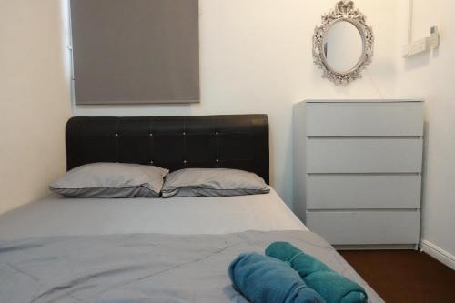 a bedroom with a bed with a black headboard and a mirror at ManMai Homestay Mesra Solat Double Storey in Nibung Tebal