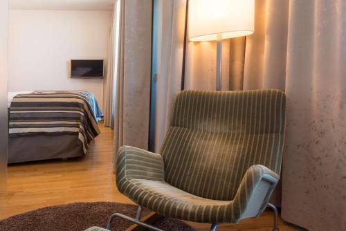 a room with a chair and a bed and a lamp at Scandic Oulu City in Oulu