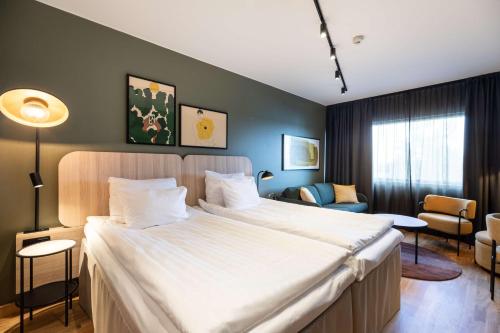 a bedroom with a large bed and a living room at Scandic Kuopio in Kuopio