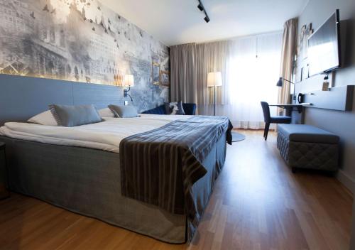 a hotel room with a large bed and a chair at Scandic Kuopio in Kuopio