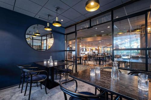 a restaurant with tables and chairs and a mirror at Scandic Kuopio in Kuopio