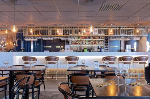 a restaurant with tables and chairs and a bar at Scandic Kuopio in Kuopio