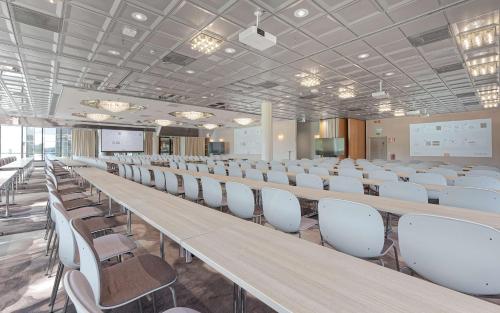 a room with rows of tables and white chairs at Scandic Kuopio in Kuopio