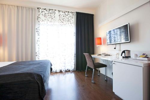 a hotel room with a bed and a desk and a window at Scandic Patria in Lappeenranta