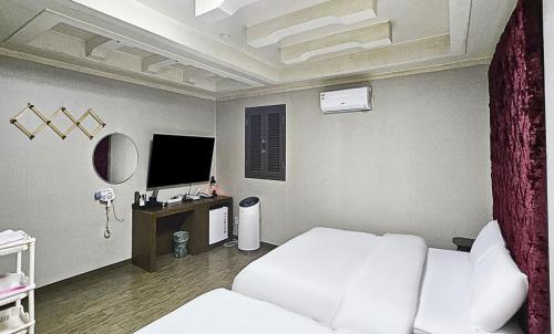 a bedroom with a white bed and a television at Nobotel Cheonan in Cheonan