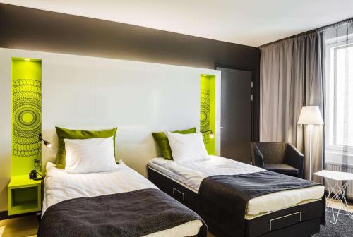 a hotel room with two beds and a chair at Scandic Tampere Station in Tampere