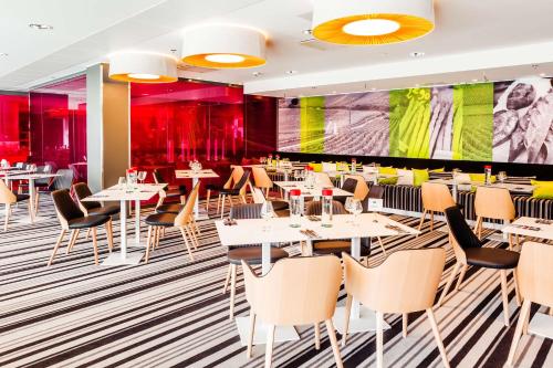 a restaurant with tables and chairs and a large screen at Scandic Tampere Station in Tampere