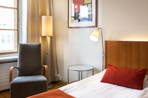 a bedroom with a bed with a red pillow and a chair at Scandic Plaza Turku in Turku