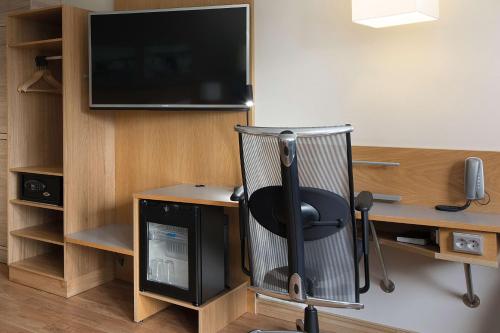 a room with a desk with a chair and a television at Scandic Asker in Asker