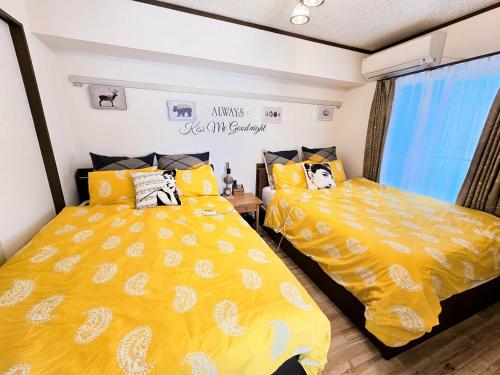 two beds in a room with yellow bedding at 101 Cozy family house in Tokyo