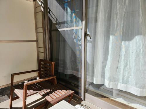 a wooden chair sitting on a balcony with a window at 101 Cozy family house in Tokyo