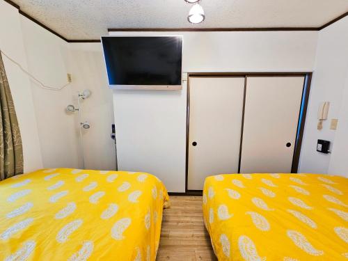 a room with two beds and a flat screen tv at 101 Cozy family house in Tokyo