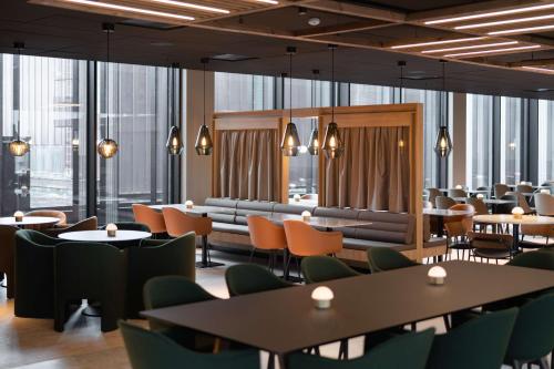 a restaurant with tables and chairs and windows at Scandic Hamar in Hamar