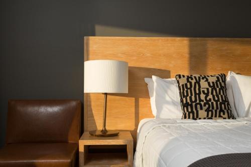 a bedroom with a bed and a chair and a lamp at Harkham Lodge in Pokolbin