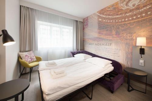 a hotel room with a large bed and a chair at Scandic St. Olavs Plass in Oslo