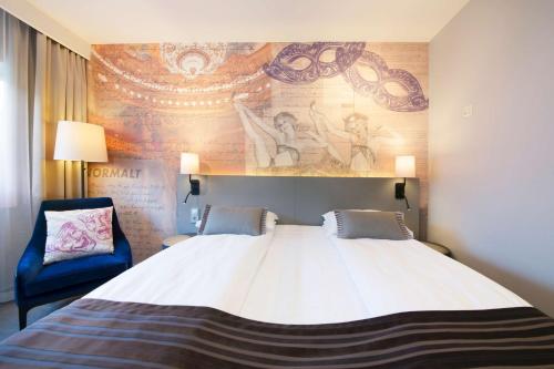 a bedroom with a large bed and a blue chair at Scandic St. Olavs Plass in Oslo