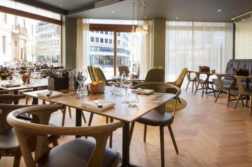 a restaurant with wooden tables and chairs and windows at Scandic St. Olavs Plass in Oslo