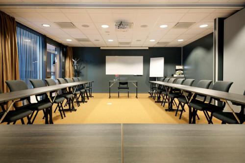 a conference room with tables and chairs and a screen at Scandic Kristiansand Bystranda in Kristiansand